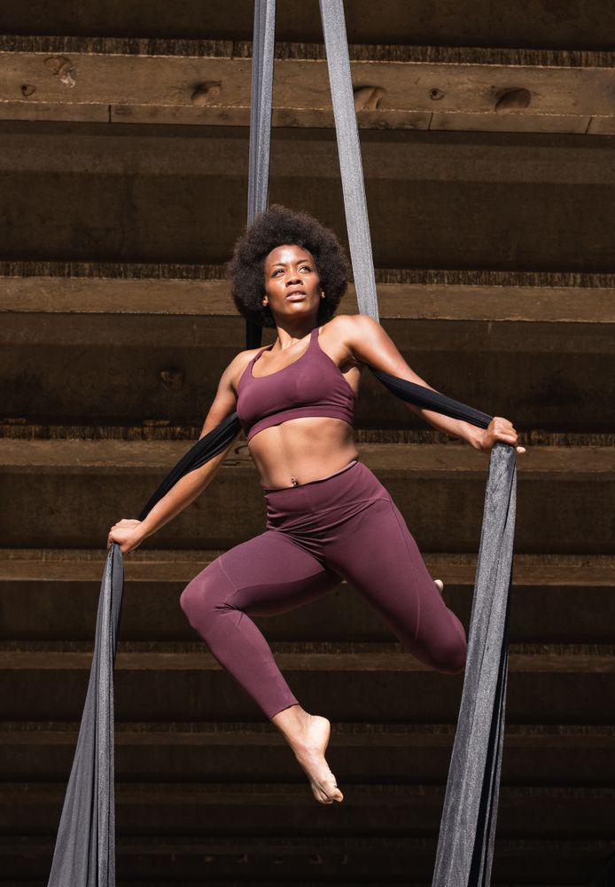 Slim woman doing yoga with aerial silks in city