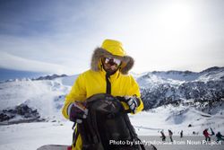 Man on mountain in yellow parka with backpack 4MOOE0