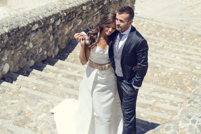 Newlyweds on outdoor stone steps on sunny day