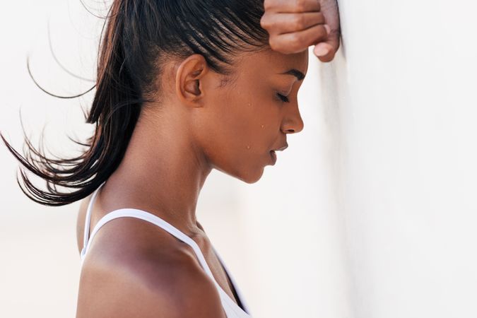 Women leaning with face on wall with eyes closed