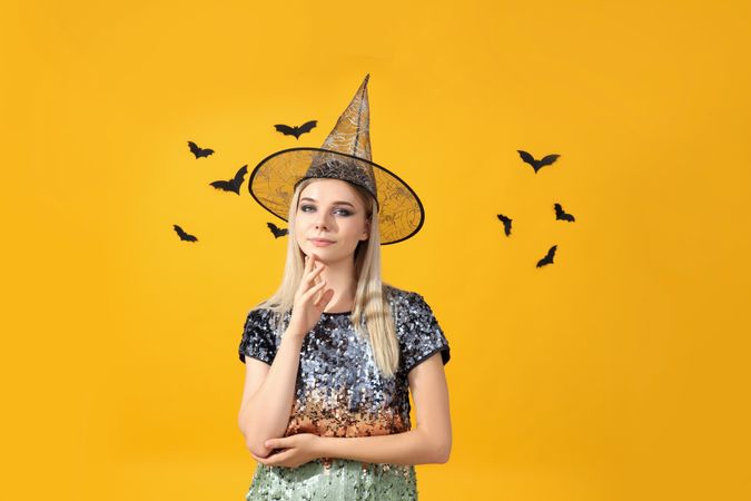 Concept of Halloween, young woman on yellow background