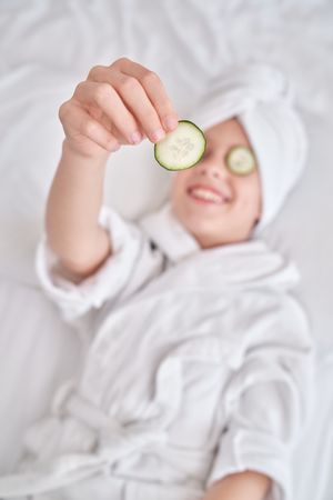 Boy in bathrobe demonstrating cucumber slice