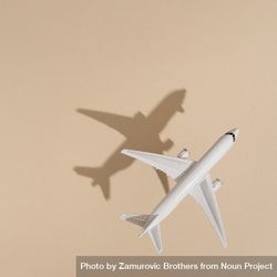 Top view of model airplane with shadow over beige paper 42nD14