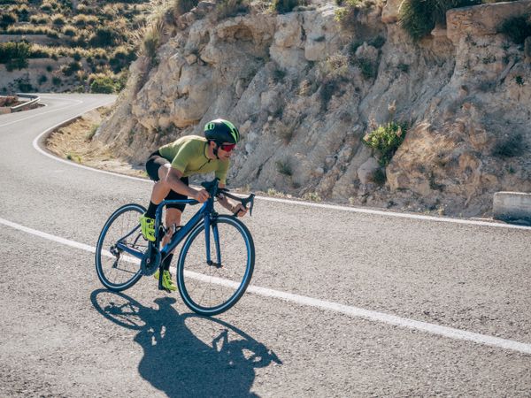 healthy man riding a bicycle on a mountain road in a sunny day