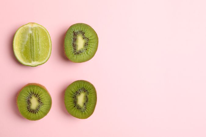 Lime and avocado on pink background, space for text