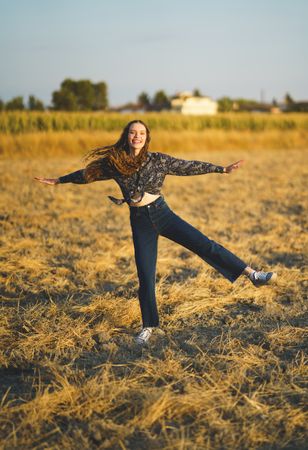 A Joyful Woman Expressively Dancing with Great Enthusiasm in a Beautiful Golden Field at Sunrise