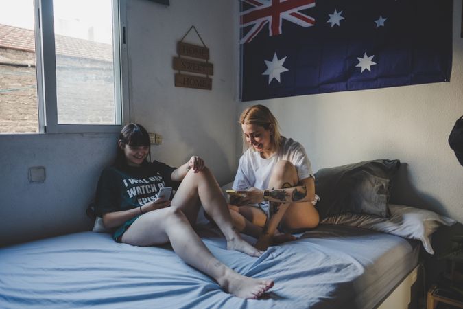 Happy lesbian couple using smartphone on bed