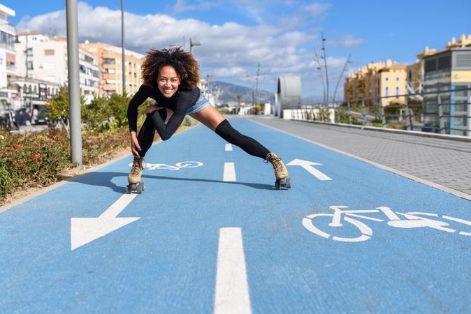 Smiling female with afro hairstyle rollerblading on sunny day