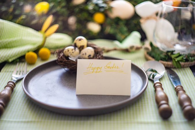 Spring table setting with Easter card on plate with decorative nest