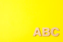 Wooden letters of English alphabet on color background, space for text