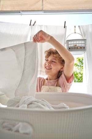 Cheerful boy doing laundry on balcony