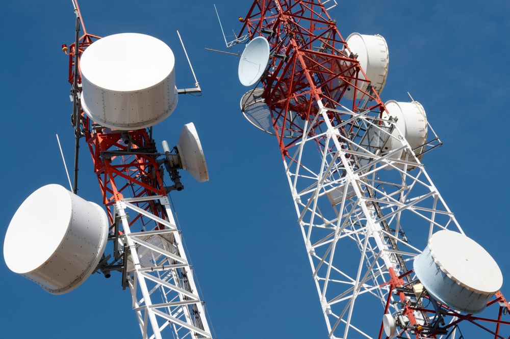 Tall Communication Towers With Dishes Against a Bright Blue Sky