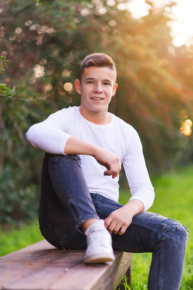 Smiling teenager sitting on park bench looking at camera