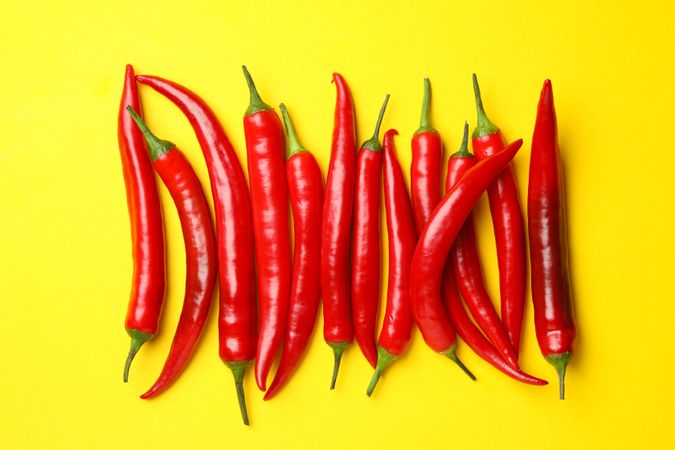 Chilli peppers on yellow background, top view