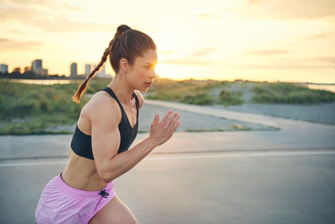 Muscular woman sprinting outside in morning light