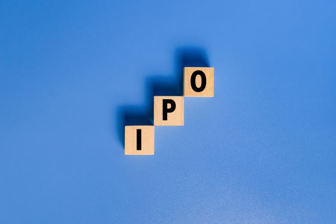 IPO letter text or initial public offering words on wooden blocks isolated on blue background copy space