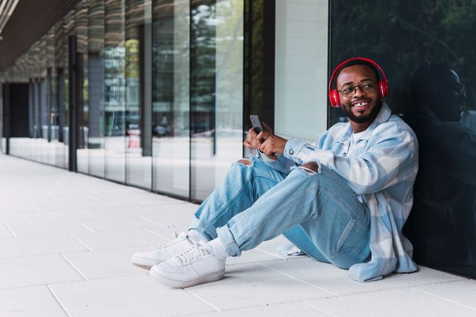 Cheerful Black man with smartphone listening to music