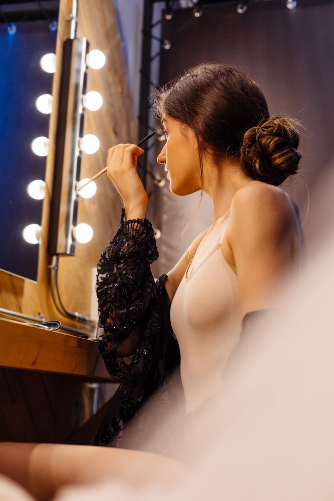 Brunette female doing makeup in front of mirror