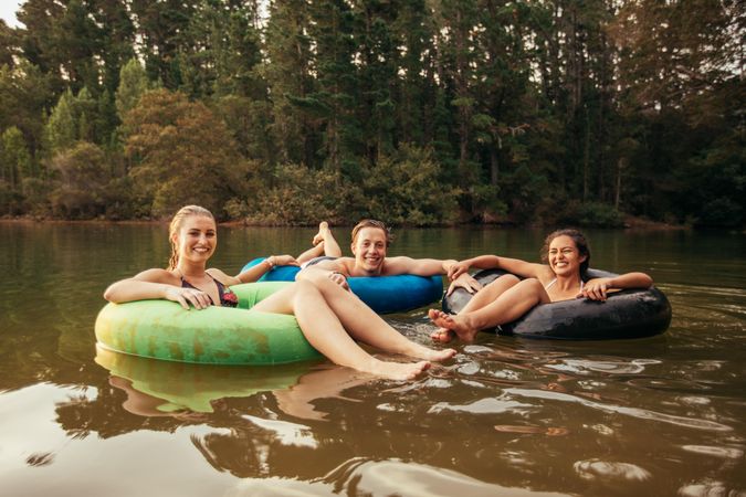 Portrait of happy young adults on inner tubes in lake