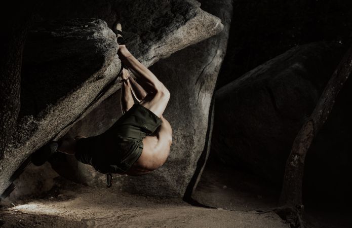 Man practicing rock climbing among large rocks in a forest
