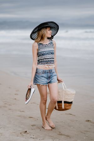 Young female walking barefoot on sandy beach