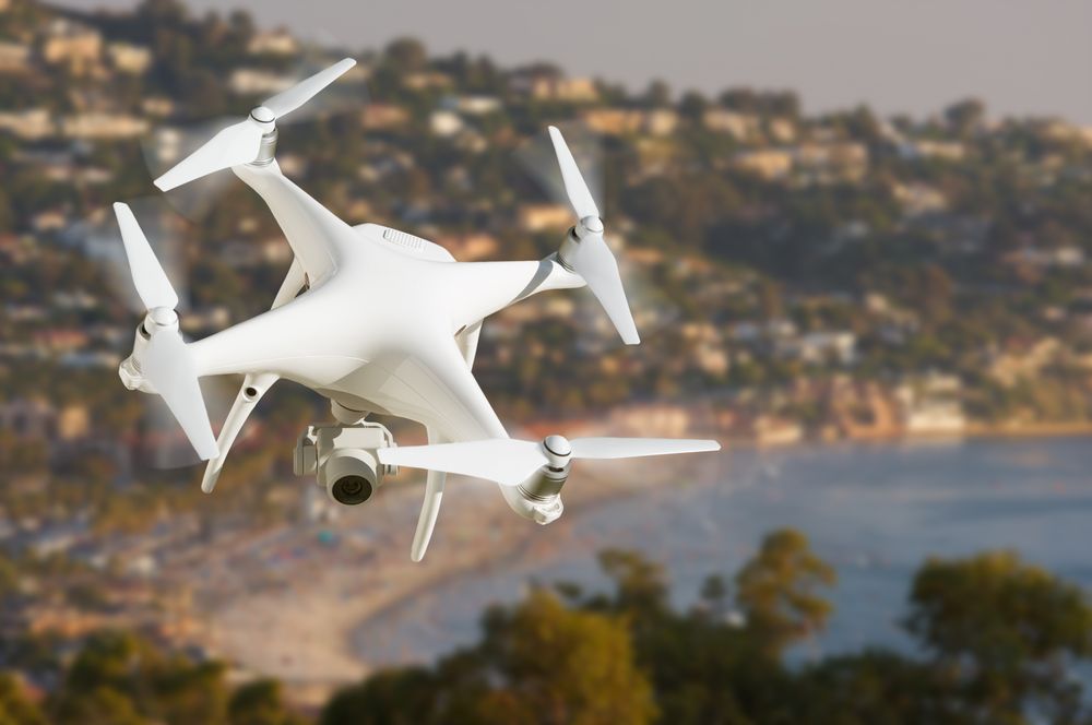 Unmanned Aircraft System (UAV) Quadcopter Drone In The Air Over The Ocean Coastline.
