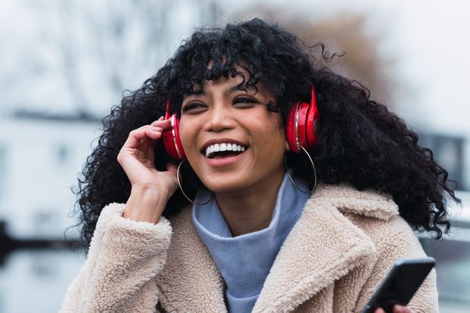 Cheerful Black woman listening to music in headphones