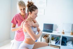 Osteopath working on upper back and shoulder of female patient