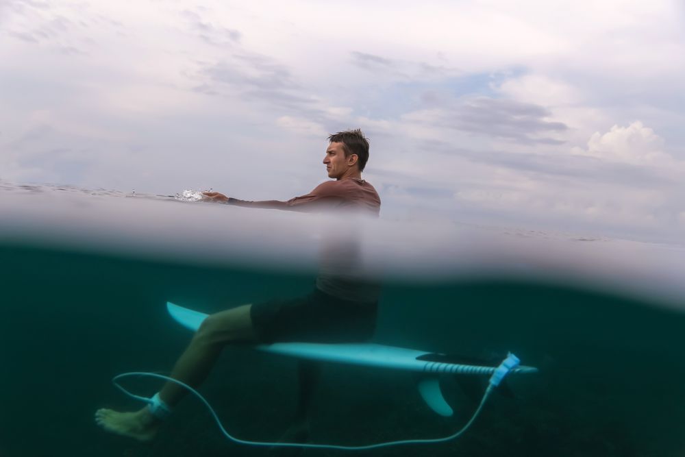 Man sitting on surf board floating in blue water