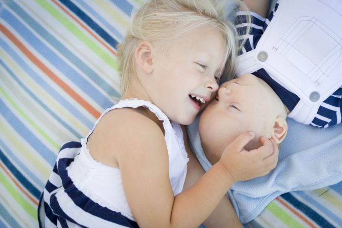 Little Sister Laying Next to Her Baby Brother on Blanket
