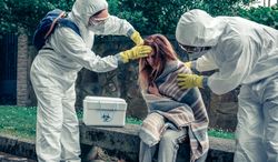 Doctors in protection suits caring for a woman