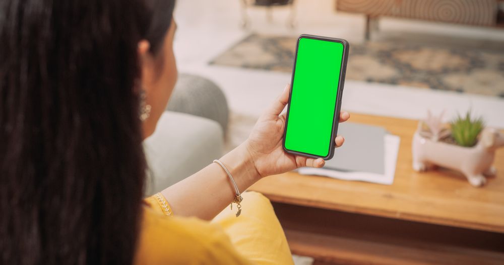 Over the Shoulder Indian Woman Using Smartphone with Green Green Screen Screen