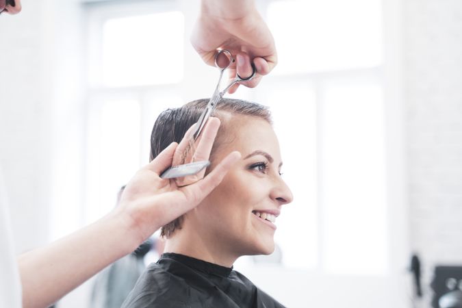 Hairdresser cuts woman's hair with scissors