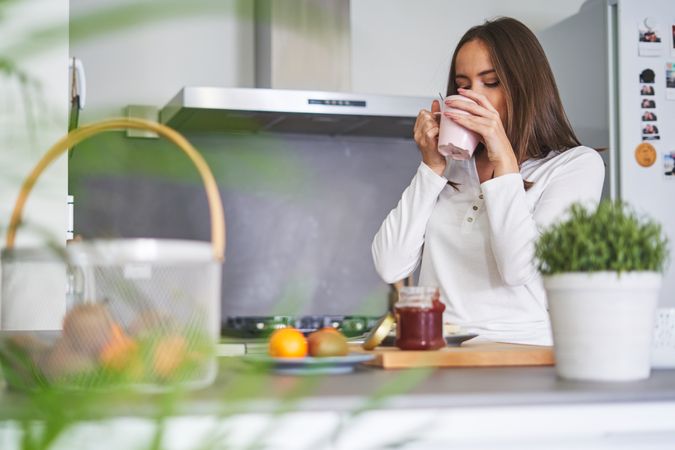 Woman drinking from cup in kitchen