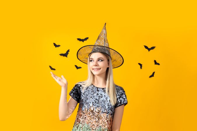 Concept of Halloween, young woman on yellow background