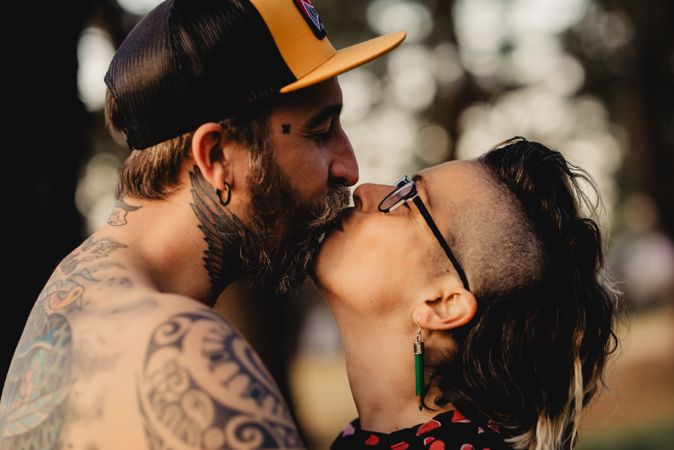 Young guy in tattoos hugging woman in forest