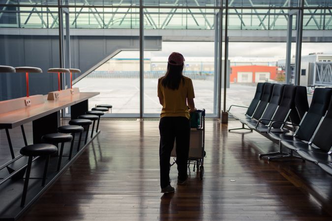 Woman walking trolley to dispatch at airport