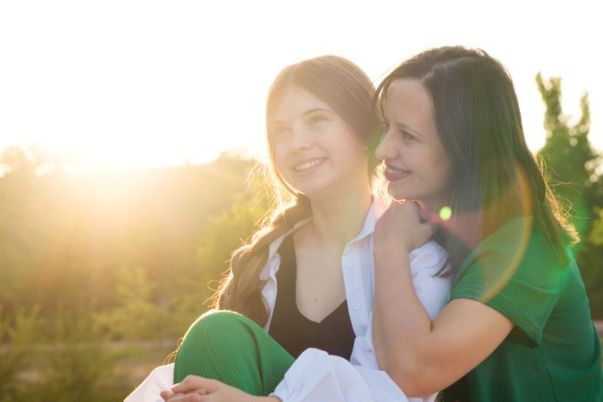 Mom and teenage daughter hugging on walk in park