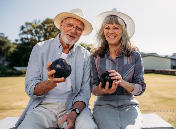 Happy man and woman sitting together in a park holding boule