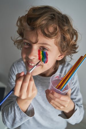 Happy child drawing rainbow on face