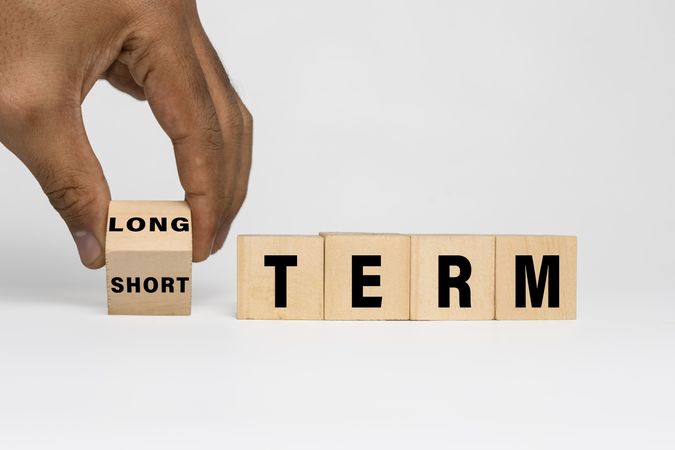 male hand flip a wooden blocks with long and short term words symbol isolated on blank background