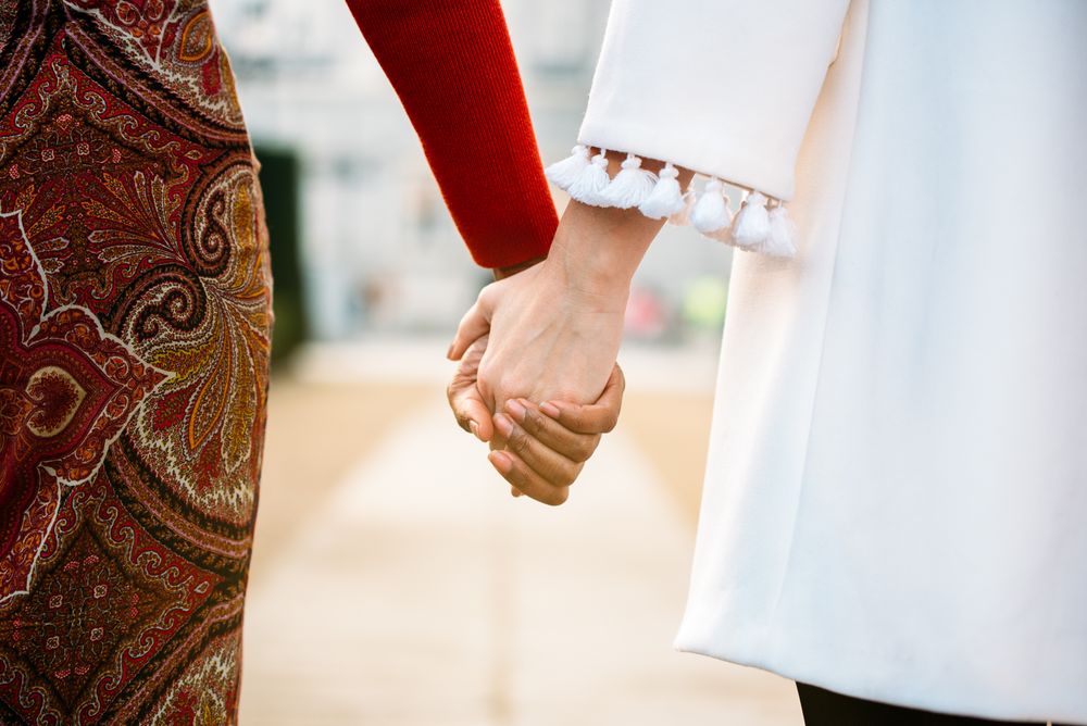 Two interracial women holding hands walking in the streets