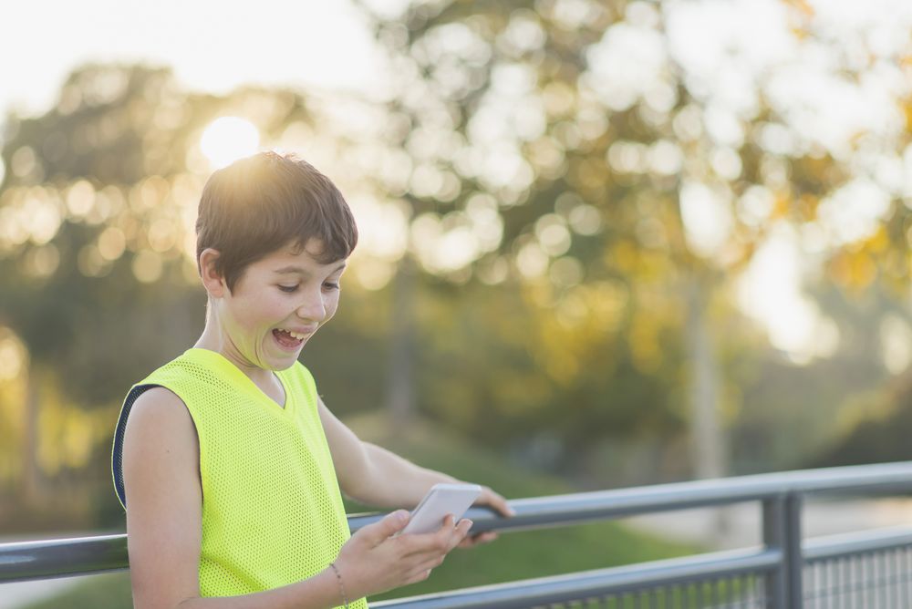 Portrait of a teenager smiling looking his smartphone