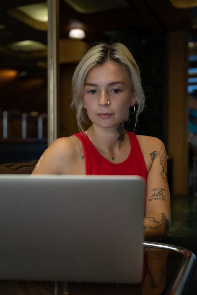Student in red tank top working on laptop computer indoor