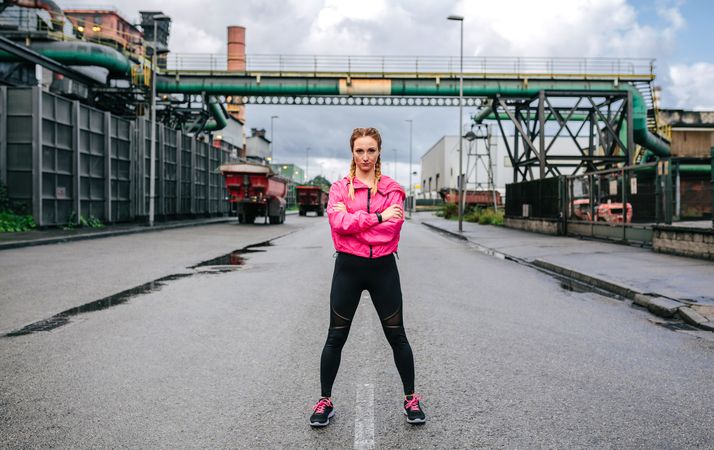 Sporty woman looking camera posing in front of a factory