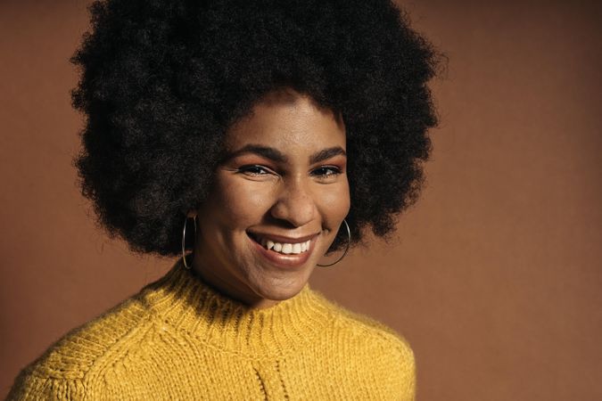 Portrait of smiling woman with Afro hair in yellow knit sweater