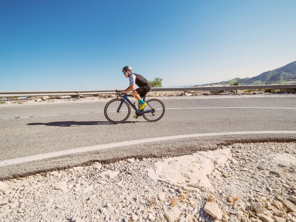 healthy man riding a bicycle on a mountain road in a sunny day
