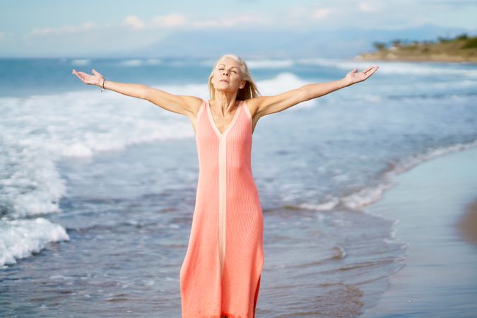Older woman with open arms on the coast
