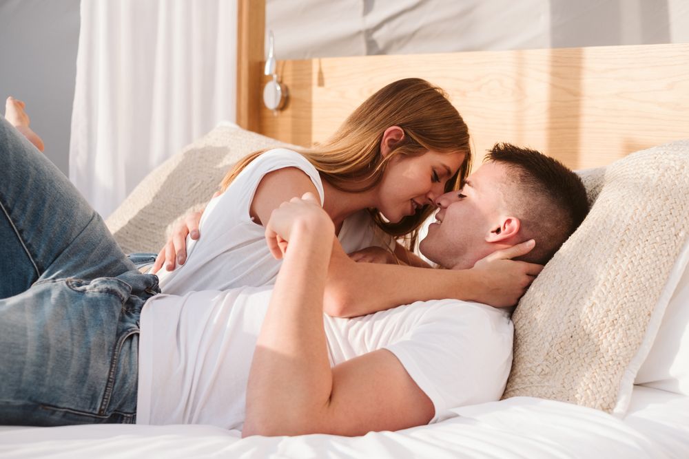 Passionate couple kissing on bed of bubble room