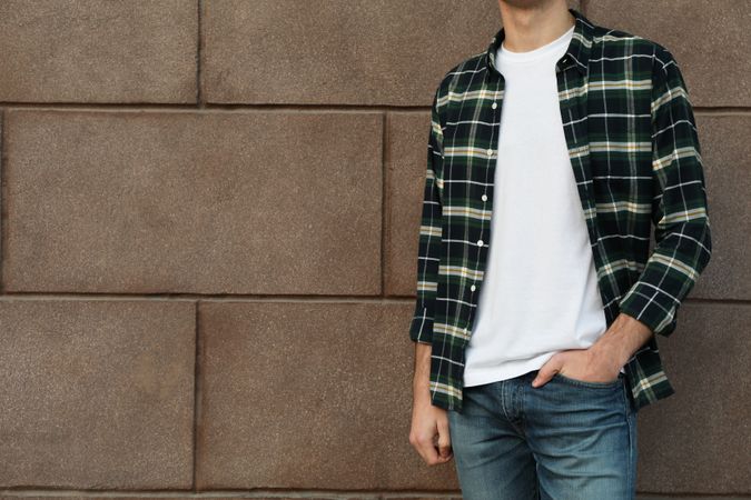 Men in t-shirt and checkered shirt against building, copy space